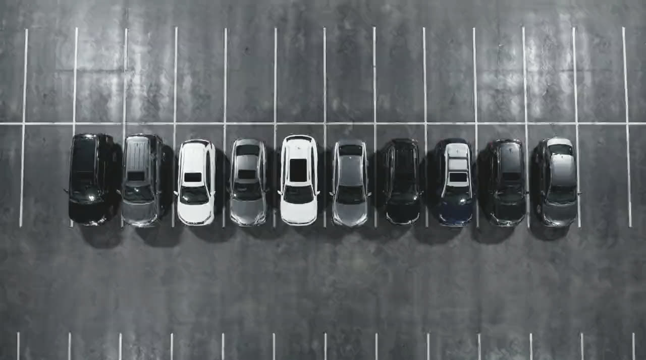 Ten cars from the fleet seen from directly overhead, parked nose in along one line of marked bays.